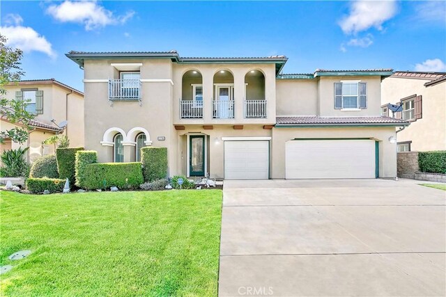 13744 Star Ruby Ave, Eastvale, CA 92880 - mediterranean / spanish home featuring a garage, a front lawn, a balcony, stucco siding, and driveway