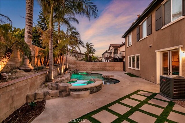 13744 Star Ruby Ave, Eastvale, CA 92880 - patio terrace at dusk featuring a fenced in pool, a fenced backyard, an in ground hot tub, and cooling unit