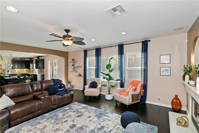 13744 Star Ruby Ave, Eastvale, CA 92880 - living room with arched walkways, baseboards, visible vents, and dark wood-type flooring