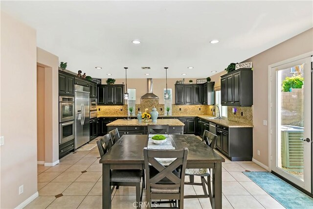 13744 Star Ruby Ave, Eastvale, CA 92880 - kitchen featuring a kitchen island, wall chimney range hood, light stone counters, a sink, and backsplash