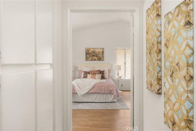 bedroom with vaulted ceiling and wood finished floors