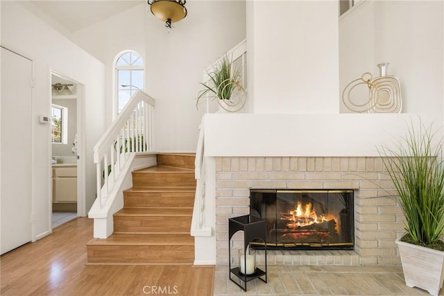 stairs with a fireplace, a high ceiling, and wood finished floors
