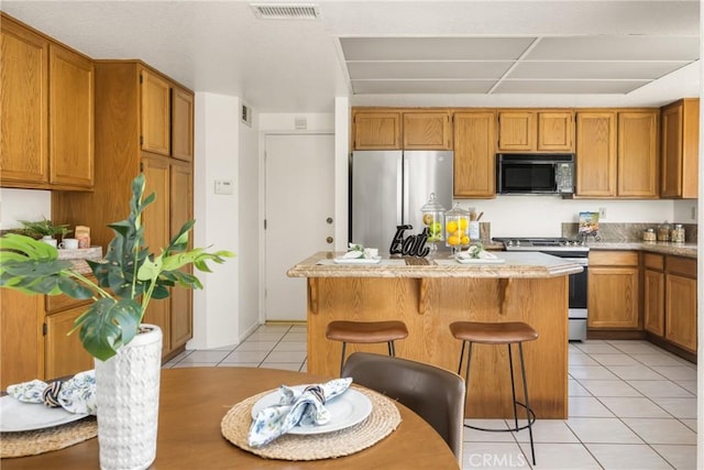kitchen featuring light tile patterned floors, a center island, visible vents, light countertops, and appliances with stainless steel finishes
