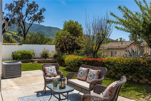 view of patio featuring a mountain view, central AC unit, fence, and an outdoor living space