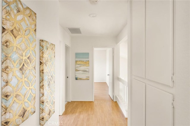 hallway with baseboards, visible vents, and light wood-type flooring