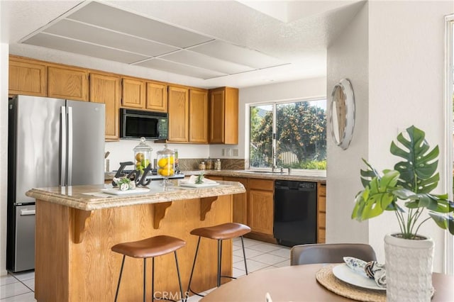 kitchen with brown cabinetry, black appliances, and light tile patterned floors