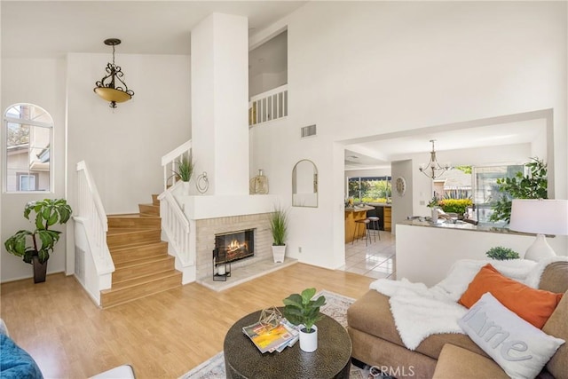 living area featuring visible vents, light wood-style flooring, a high ceiling, and stairs