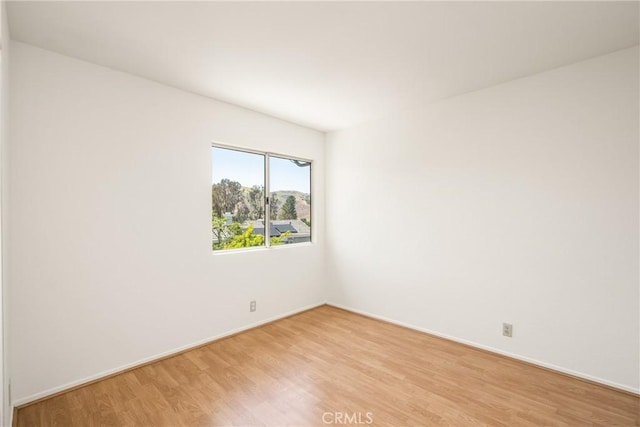 empty room featuring baseboards and light wood-type flooring