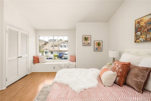 bedroom featuring baseboards, lofted ceiling, a closet, and wood finished floors