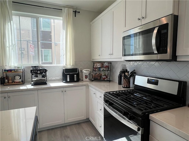 3530 E Delight Paseo Unit 205, Ontario, CA 91761 - kitchen featuring appliances with stainless steel finishes, white cabinetry, tasteful backsplash, and light wood-type flooring