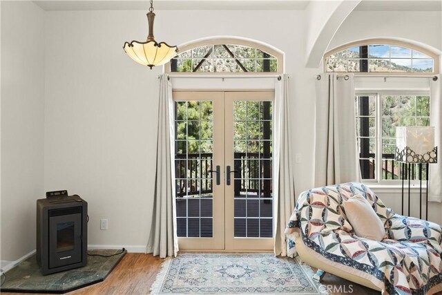 doorway featuring baseboards, french doors, a wood stove, and wood finished floors