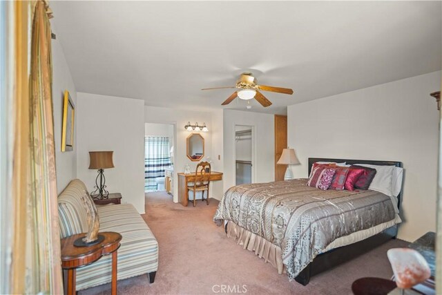 bedroom with a spacious closet, a ceiling fan, and light colored carpet