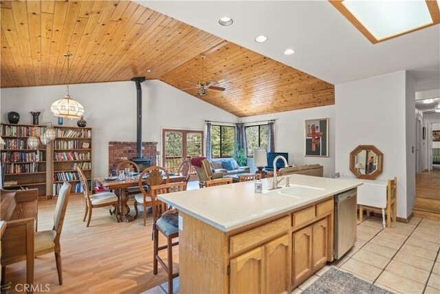 kitchen featuring a sink, a wood stove, a ceiling fan, open floor plan, and stainless steel dishwasher
