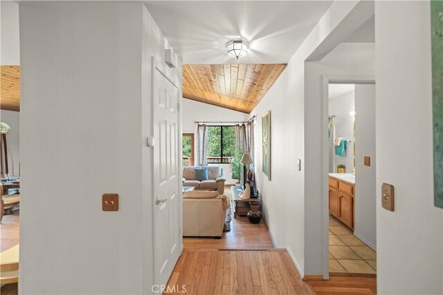 hall with baseboards, wooden ceiling, lofted ceiling, and light wood-type flooring