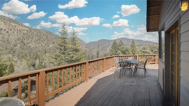 wooden terrace featuring outdoor dining space and a mountain view