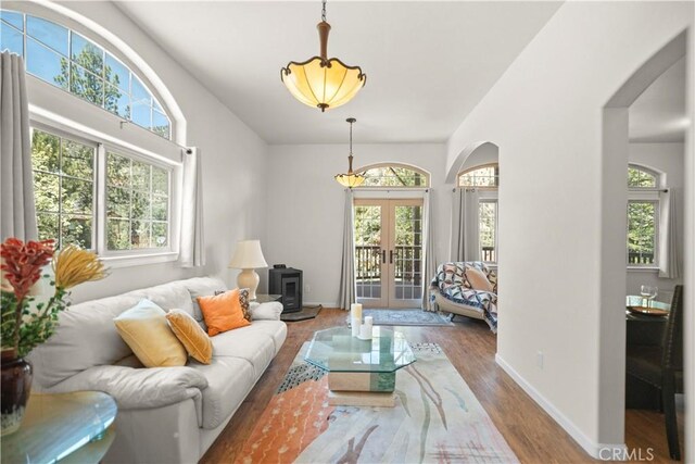 living area with french doors, arched walkways, baseboards, and wood finished floors
