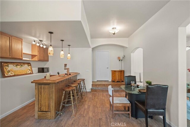 interior space with indoor bar, arched walkways, baseboards, and dark wood finished floors