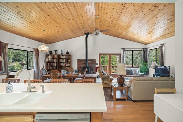 kitchen with ceiling fan, a sink, a wood stove, open floor plan, and lofted ceiling