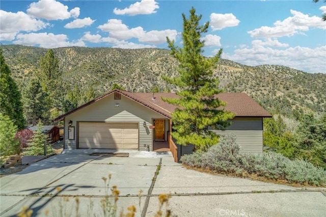 single story home with a garage, a mountain view, and concrete driveway