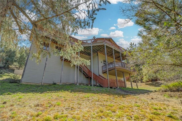 rear view of property featuring a yard, a wooden deck, and stairs