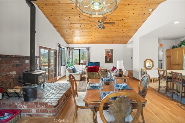 dining space with a wood stove, ceiling fan, high vaulted ceiling, wood ceiling, and light wood-style flooring
