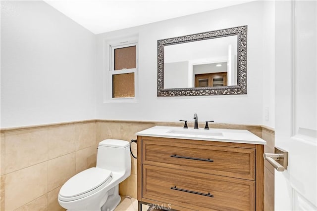 half bath with wainscoting, tile walls, vanity, and toilet