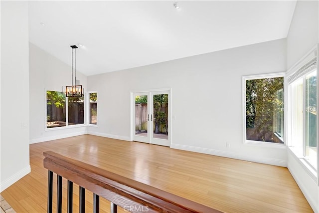 unfurnished dining area with french doors, an inviting chandelier, plenty of natural light, and light wood-style flooring