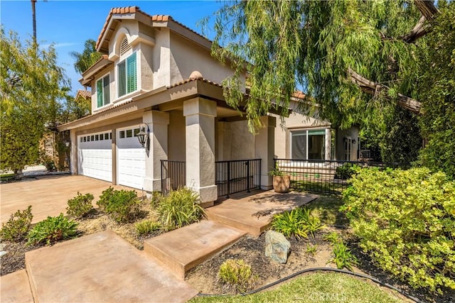 mediterranean / spanish home with a garage, fence, stucco siding, concrete driveway, and a tile roof
