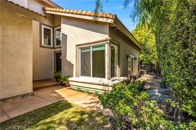 rear view of house with stucco siding and fence