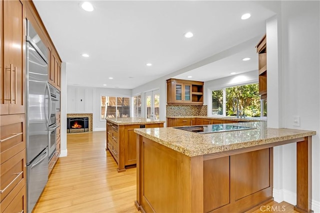 kitchen with brown cabinets, a peninsula, open shelves, and black electric stovetop