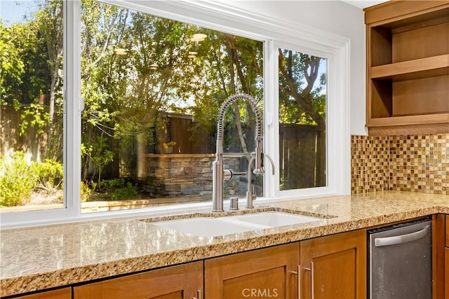 interior space featuring stainless steel dishwasher, decorative backsplash, and a sink