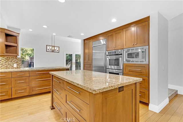 kitchen featuring open shelves, light stone counters, light wood-style floors, built in appliances, and tasteful backsplash