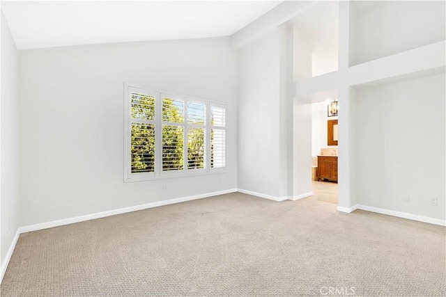 unfurnished room featuring baseboards, high vaulted ceiling, and light carpet