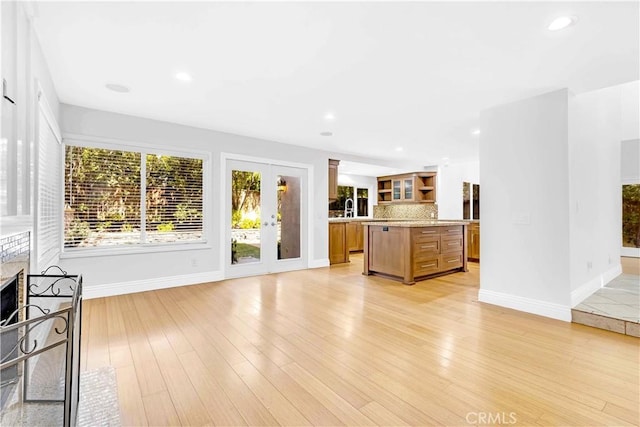 unfurnished living room featuring recessed lighting, baseboards, a sink, and light wood-style flooring