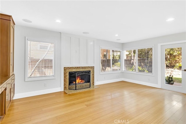 unfurnished living room with light wood-style floors, plenty of natural light, baseboards, and a fireplace