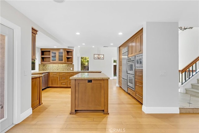 kitchen with open shelves, appliances with stainless steel finishes, brown cabinetry, light wood-style flooring, and decorative backsplash