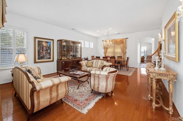 living area featuring arched walkways, recessed lighting, wood finished floors, and a chandelier