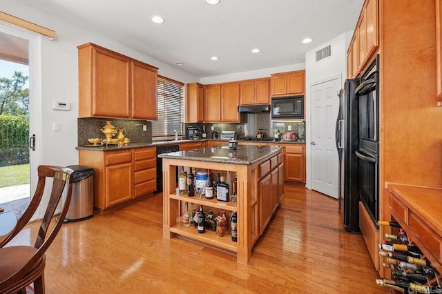 kitchen with visible vents, light wood finished floors, black appliances, and tasteful backsplash