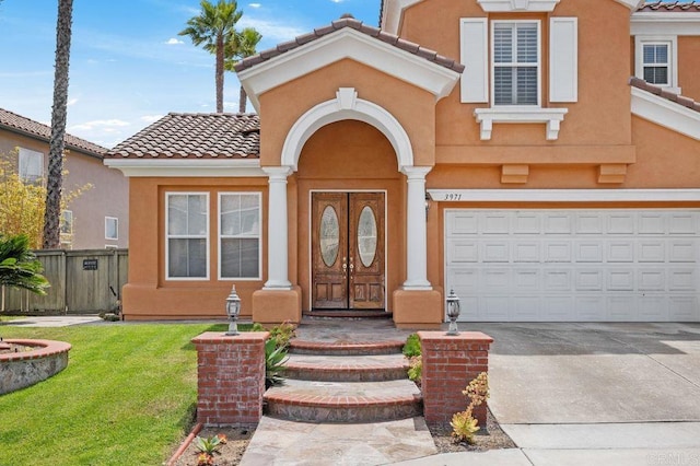 entrance to property featuring fence, a tiled roof, driveway, and stucco siding