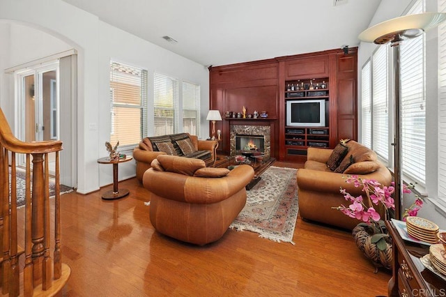 living room with a lit fireplace, wood finished floors, and visible vents