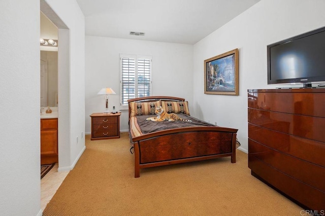 bedroom with baseboards, visible vents, ensuite bath, and light colored carpet