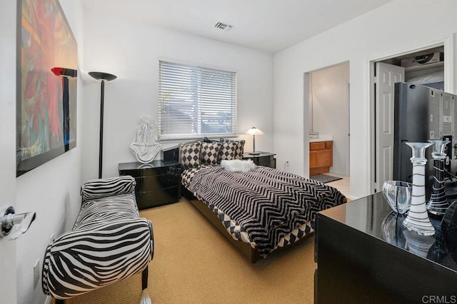 carpeted bedroom featuring ensuite bathroom and visible vents