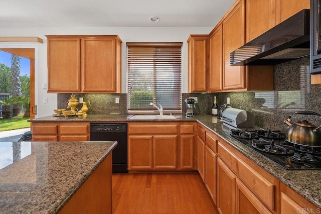 kitchen with a sink, under cabinet range hood, black appliances, and a wealth of natural light