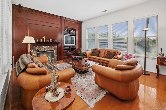living area featuring baseboards, visible vents, wood finished floors, and a fireplace