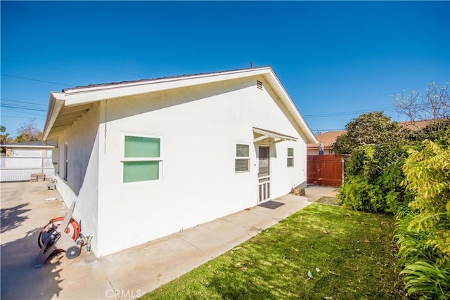 945 10th St, Huntington Beach, CA 92648 - view of side of home featuring fence, stucco siding, and a yard