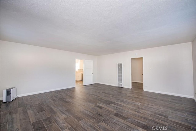 945 10th St, Huntington Beach, CA 92648 - empty room with baseboards, a heating unit, dark wood finished floors, and a textured ceiling