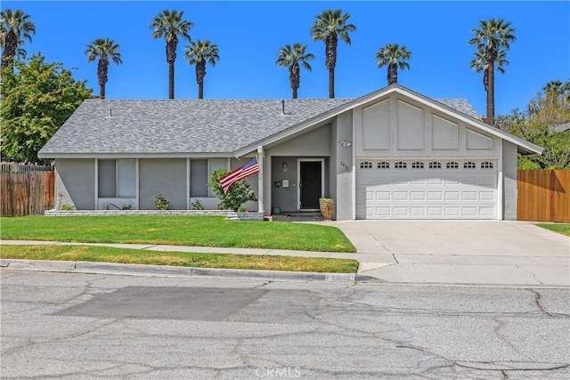 view of front of property featuring a front lawn, fence, stucco siding, concrete driveway, and an attached garage