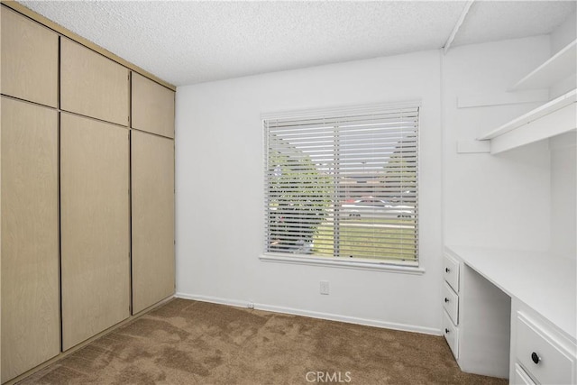 unfurnished bedroom featuring baseboards, a textured ceiling, carpet, and a closet