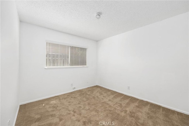 spare room with baseboards, carpet, and a textured ceiling