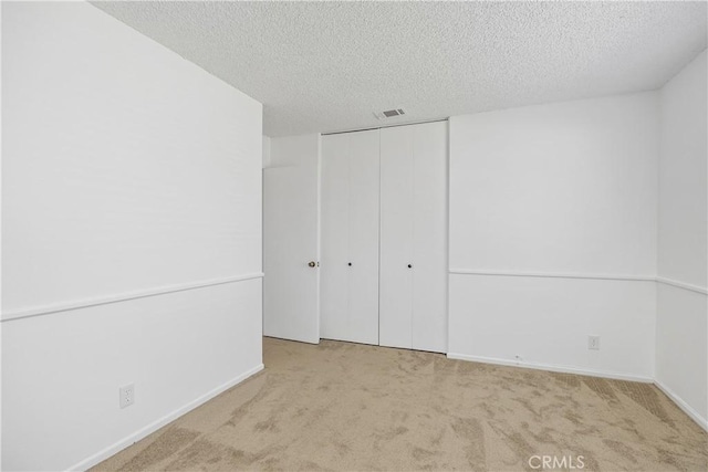 unfurnished bedroom with carpet floors, a textured ceiling, baseboards, and a closet